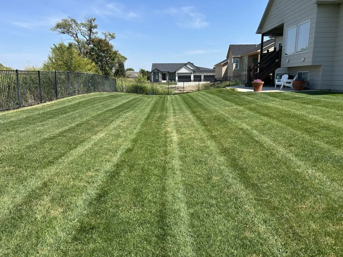 Professional lawn care team mowing and maintaining a lush green residential lawn in Wichita Kansas